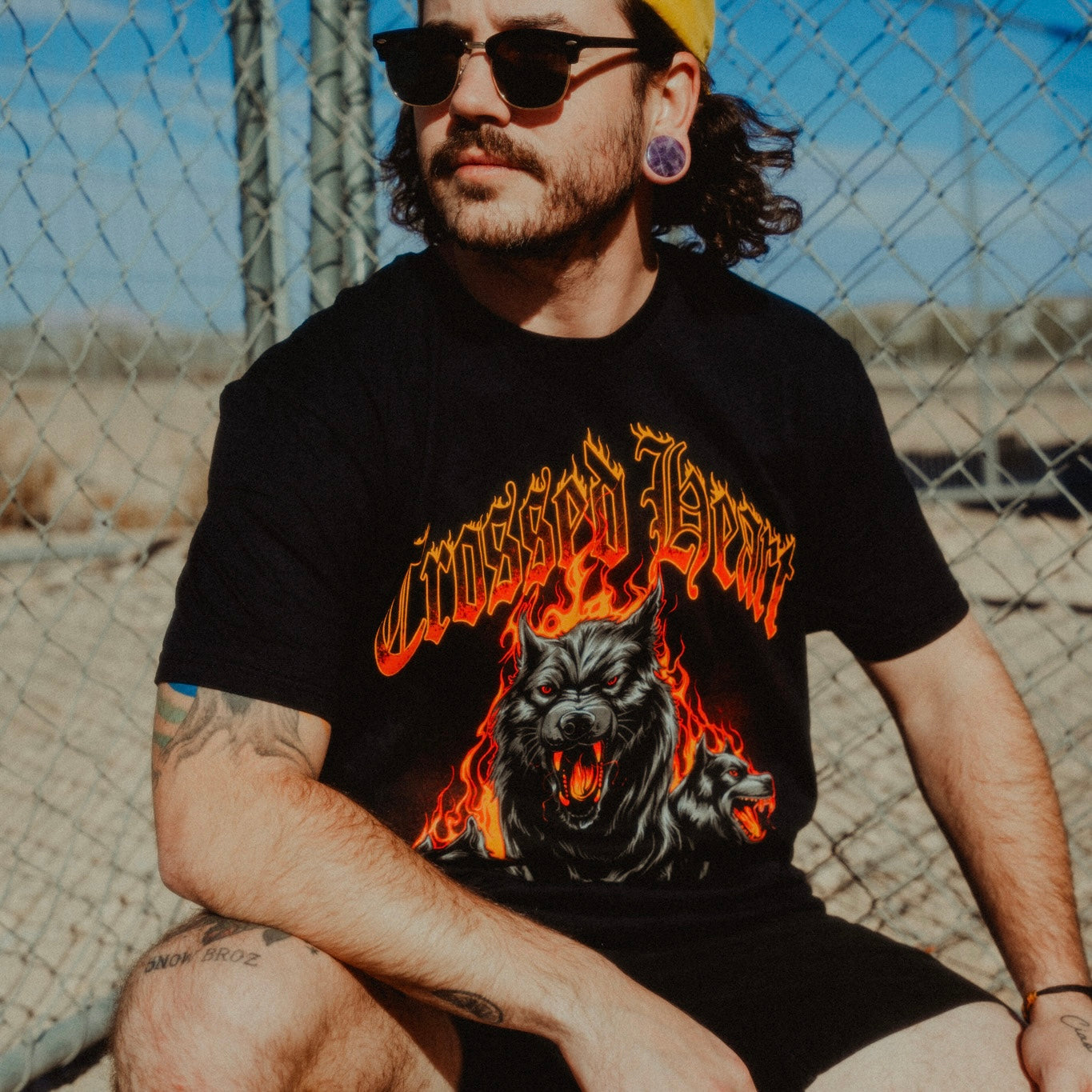 Man wearing black alternative streetwear Dogs of War t-shirt featuring flaming three-headed hellhound graphic by Crossed Heart Clothing