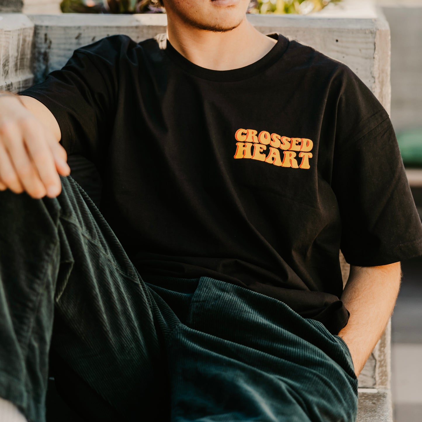 close up of black protect your peace t shirt with small crossed heart chest graphic streetwear detail