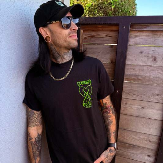 person wearing black graphic t-shirt with green crossed heart logo streetwear band merch lifestyle photo