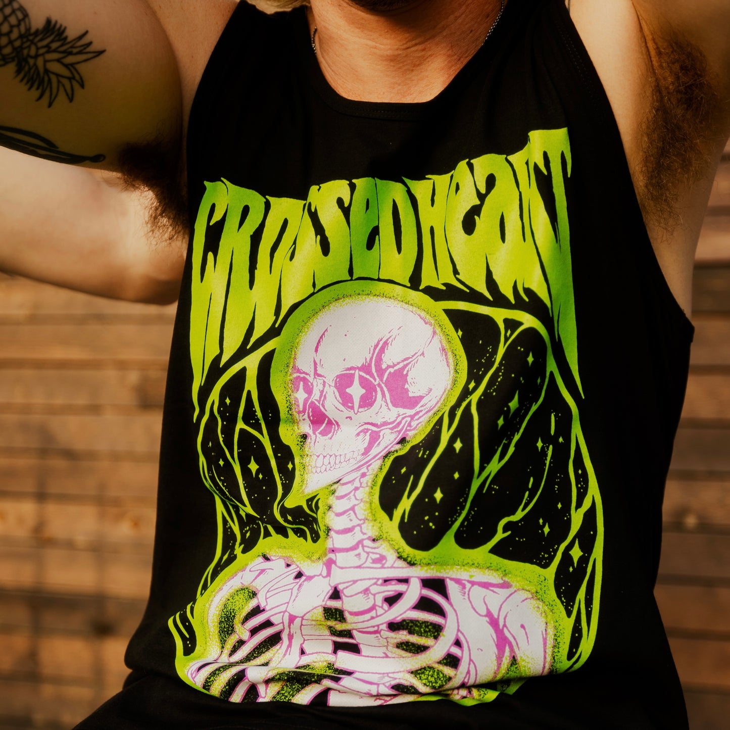 Person wearing black alternative streetwear tank featuring neon green and pink skeleton graphic Alchemist design by Crossed Heart Clothing