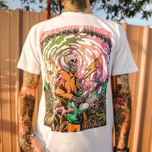 Lifestyle photo of Underwater graphic t-shirt by Crossed Heart Clothing featuring psychedelic skeleton astronaut playing guitar design on white alternative streetwear tee